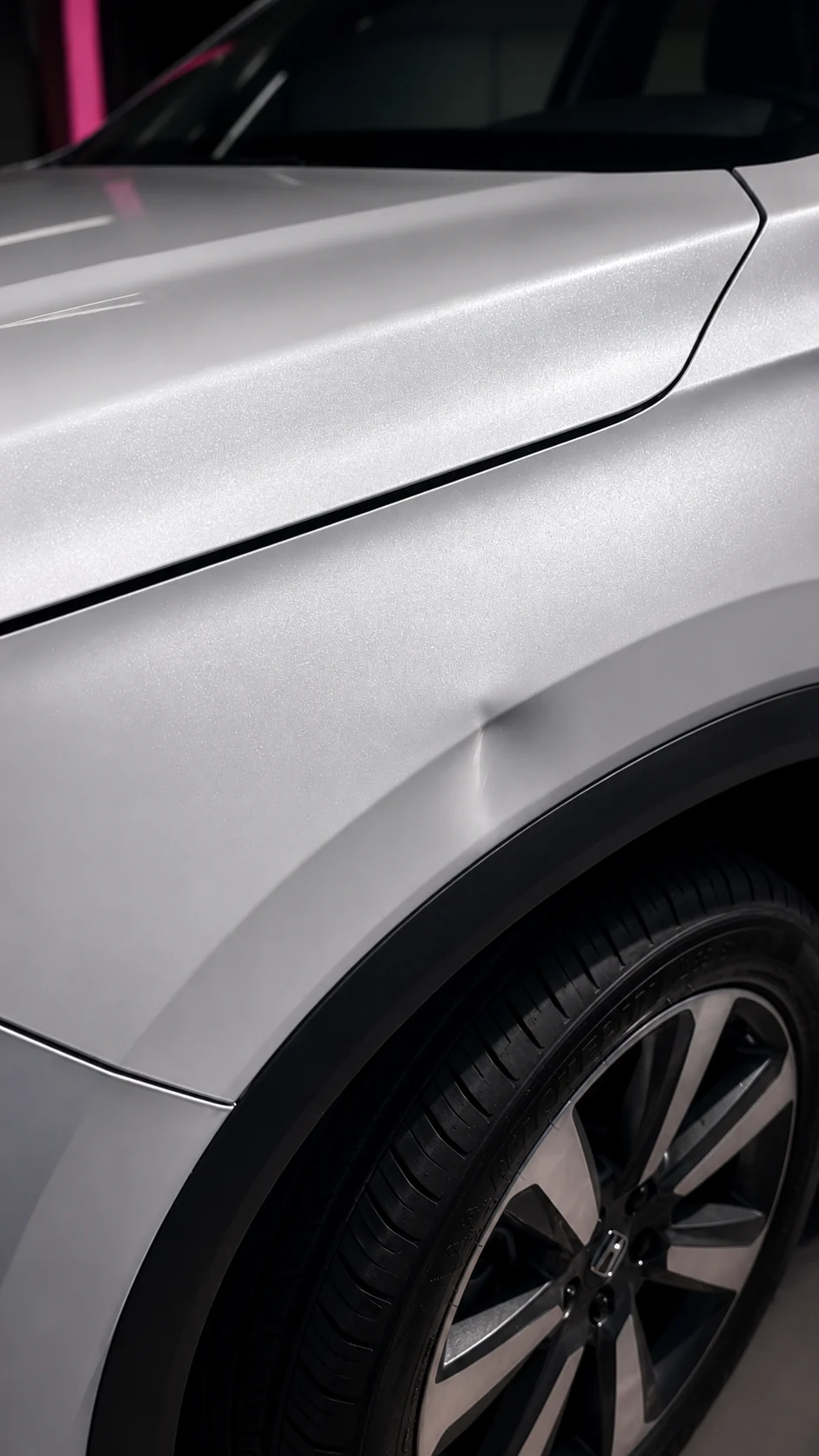 Close-up of dent on white vehicle fender